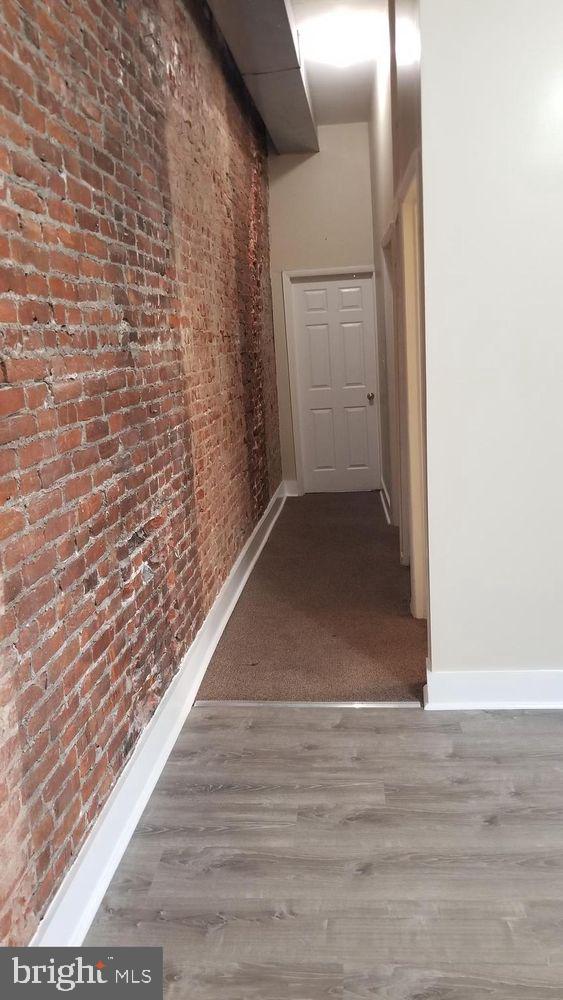 1921 W Diamond St, Philadelphia, PA 19121 - hall featuring baseboards, wood finished floors, and brick wall