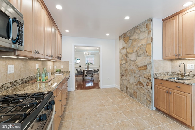 142 N French St, Alexandria, VA 22304 - kitchen featuring a sink, appliances with stainless steel finishes, light tile patterned flooring, light stone countertops, and backsplash
