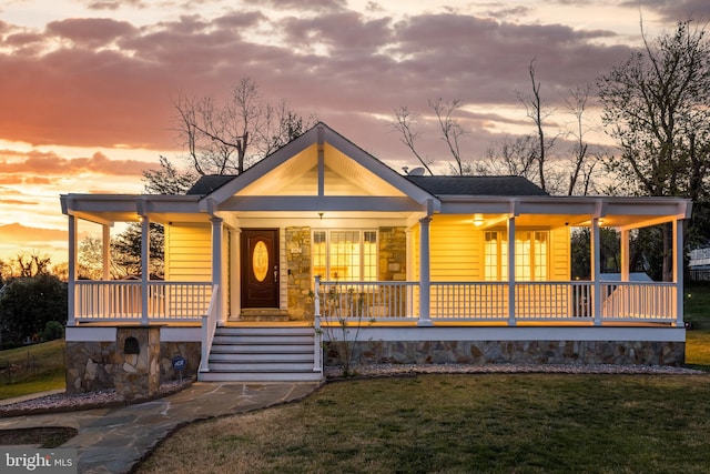 view of front of house with a front yard, a porch, and stone siding