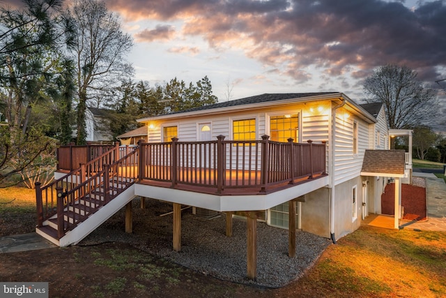 back of house at dusk with stairs and a wooden deck