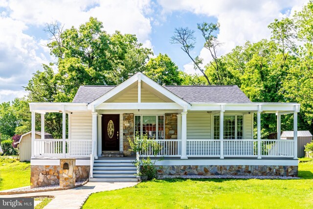 142 N French St, Alexandria, VA 22304 - view of front of house with a porch, roof with shingles, stone siding, and a storage shed
