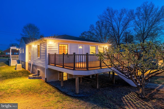 back of house featuring stairway, a deck, and a lawn
