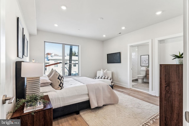 bedroom with recessed lighting, light wood finished floors, baseboards, and ensuite bathroom