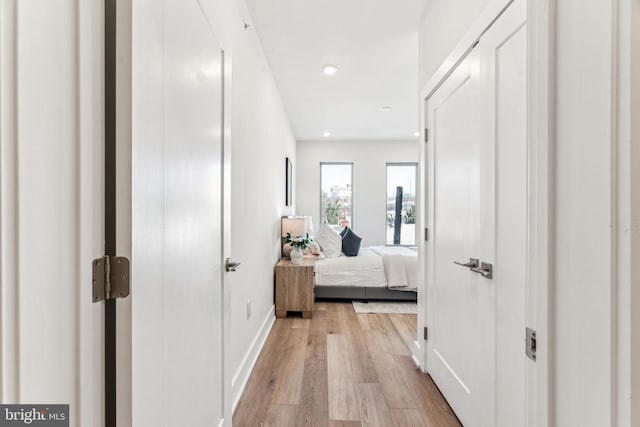 hall with baseboards, light wood finished floors, and recessed lighting