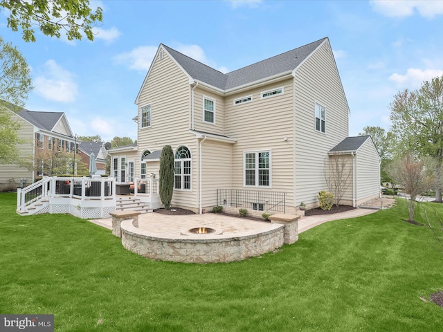 back of property with a fire pit, a yard, a patio area, and a wooden deck