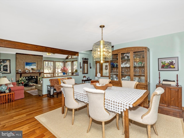 10334 Harp Rd, Walkersville, MD 21793 - dining space with beamed ceiling, a brick fireplace, wood finished floors, and a notable chandelier