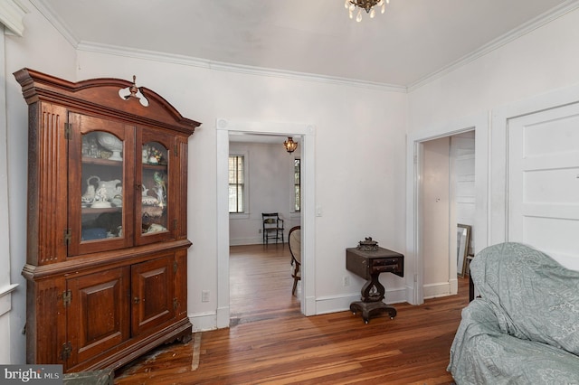 living area with a notable chandelier, crown molding, baseboards, and wood finished floors