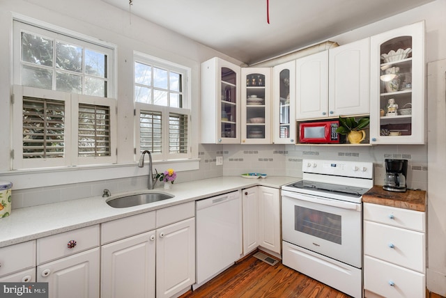 kitchen featuring white appliances, backsplash, white cabinets, and a sink
