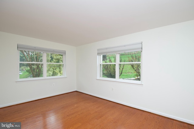 spare room featuring a healthy amount of sunlight, wood finished floors, and baseboards