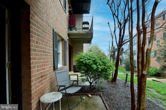 view of side of property with brick siding, a balcony, and fence
