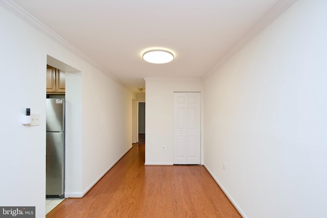 hall featuring light wood-type flooring, crown molding, and baseboards