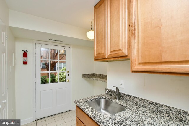 kitchen with light stone counters, light tile patterned flooring, a sink, and visible vents