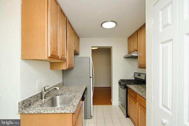 kitchen featuring a sink, appliances with stainless steel finishes, under cabinet range hood, light stone countertops, and light tile patterned flooring