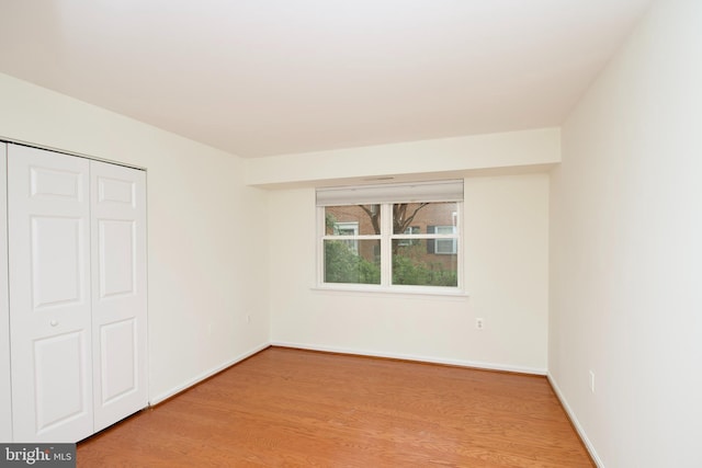 unfurnished bedroom featuring a closet, light wood finished floors, and baseboards