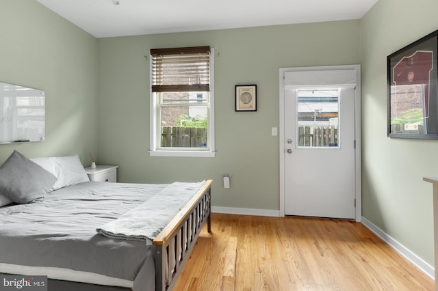 bedroom with multiple windows, wood finished floors, and baseboards