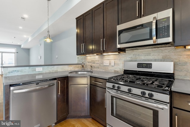 kitchen with a sink, stainless steel appliances, a peninsula, and tasteful backsplash