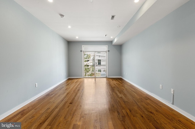 unfurnished room featuring baseboards, wood finished floors, and recessed lighting