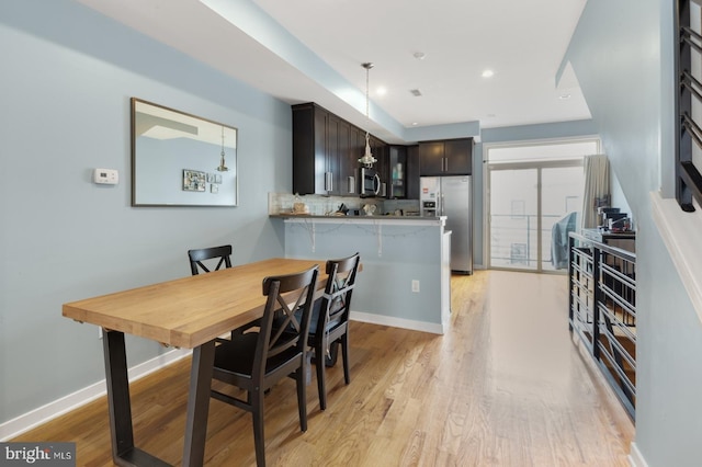 dining area with baseboards, light wood-type flooring, and recessed lighting