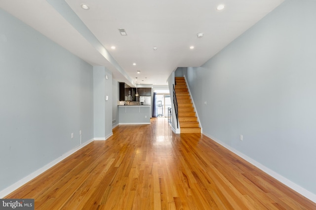 unfurnished living room featuring recessed lighting, baseboards, and light wood-type flooring