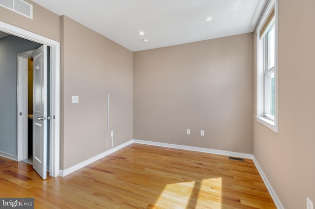 empty room featuring plenty of natural light, light wood finished floors, and visible vents