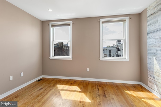 spare room featuring light wood-style flooring, baseboards, and visible vents