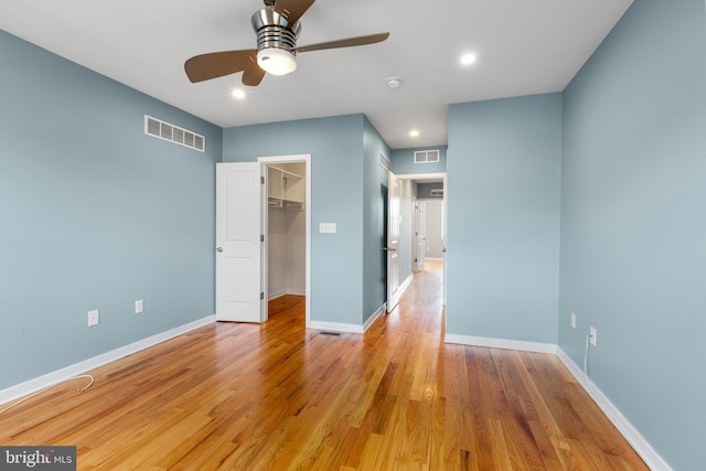 unfurnished bedroom with baseboards, visible vents, light wood-style flooring, and a spacious closet