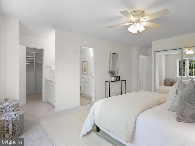 bedroom featuring ceiling fan, a closet, a spacious closet, light carpet, and ensuite bath