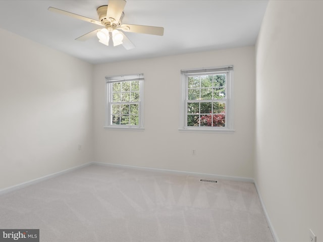 unfurnished room with carpet floors, baseboards, visible vents, and a wealth of natural light