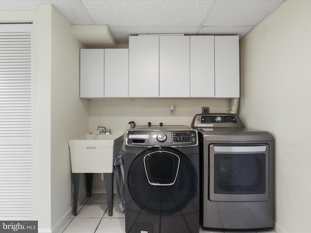 laundry room featuring baseboards, washer and clothes dryer, a sink, cabinet space, and light tile patterned floors