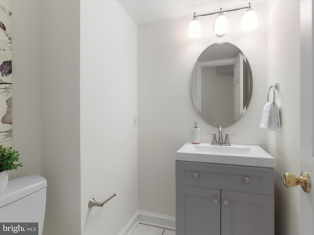 bathroom featuring vanity, baseboards, tile patterned floors, and toilet