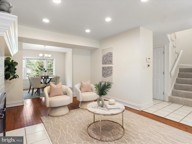 living area featuring baseboards, stairs, wood finished floors, and a notable chandelier
