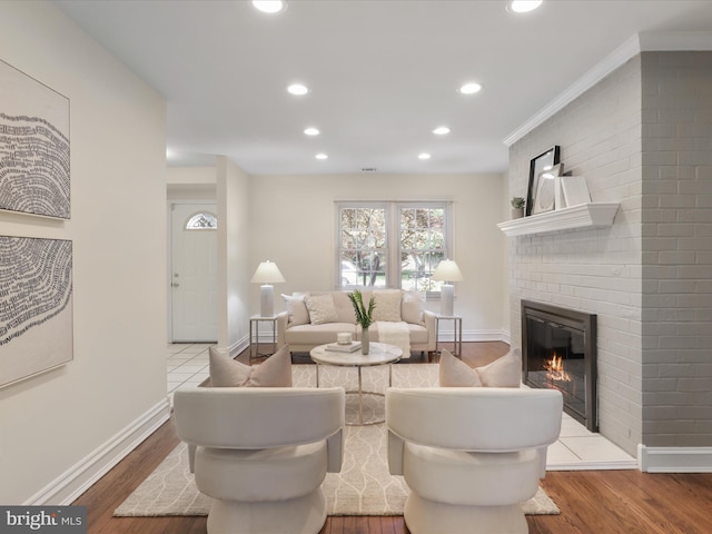 living room featuring recessed lighting, baseboards, a brick fireplace, and wood finished floors