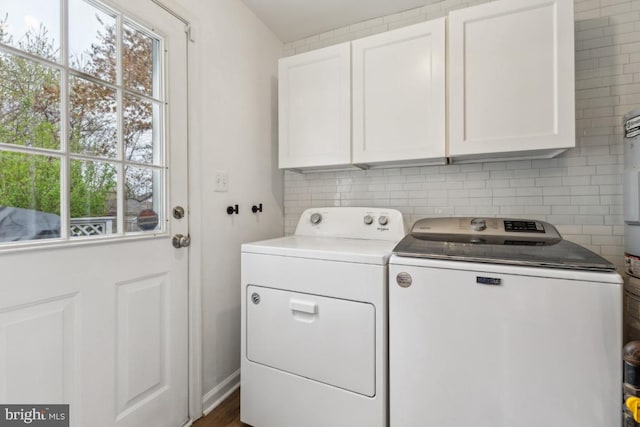 washroom featuring cabinet space, washer and clothes dryer, and a healthy amount of sunlight