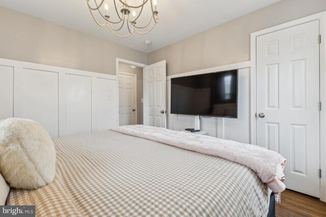 bedroom featuring an inviting chandelier and dark wood-style floors