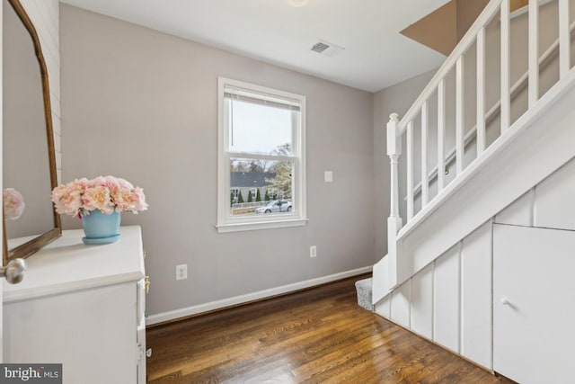 staircase featuring visible vents, baseboards, and wood finished floors