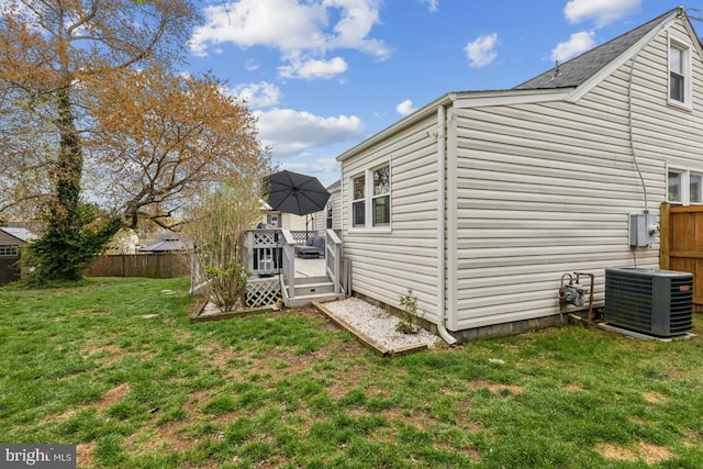 view of side of home featuring a deck, a lawn, fence, and central AC