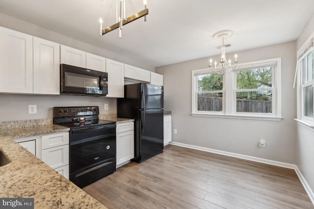 kitchen with white cabinets, light wood-style flooring, black appliances, and a notable chandelier