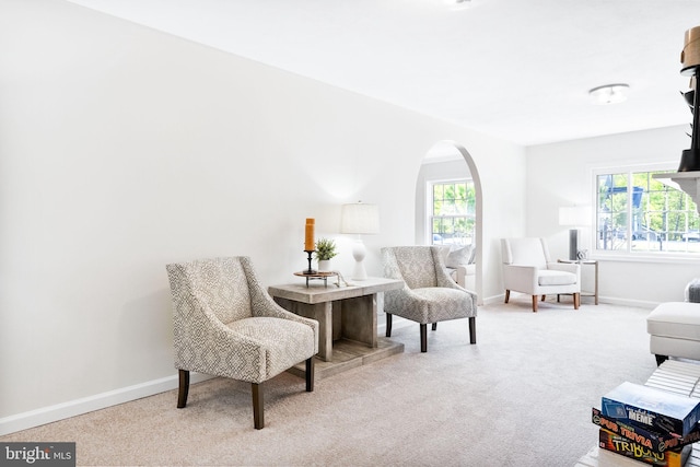 sitting room with carpet floors, arched walkways, baseboards, and a wealth of natural light