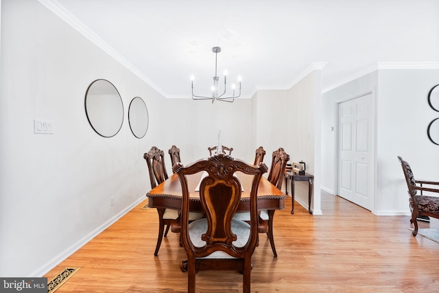 dining space with crown molding, an inviting chandelier, and light wood-style flooring