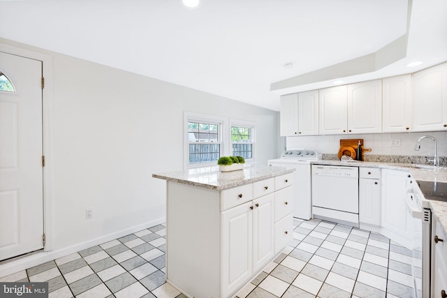 kitchen with white dishwasher, a center island, a sink, washer / dryer, and white cabinetry