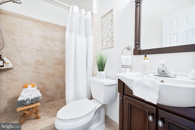 bathroom with vanity, toilet, and tiled shower