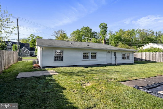 rear view of property featuring a lawn, a fenced backyard, and a patio