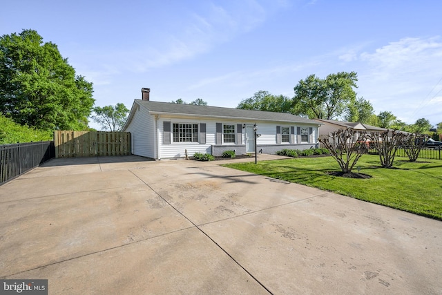 ranch-style home featuring fence, a chimney, driveway, and a front lawn