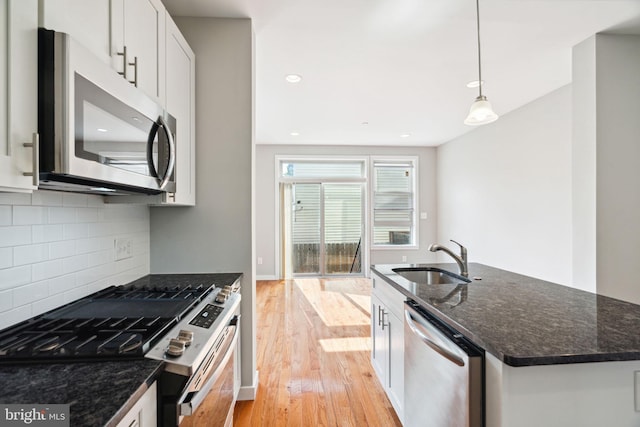 1256 S 27th St, Philadelphia, PA 19146 - kitchen featuring light wood-style floors, dark stone counters, a sink, stainless steel appliances, and decorative backsplash