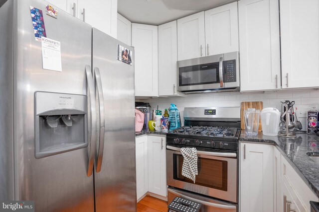 1256 S 27th St, Philadelphia, PA 19146 - kitchen featuring backsplash, white cabinets, dark stone counters, and stainless steel appliances