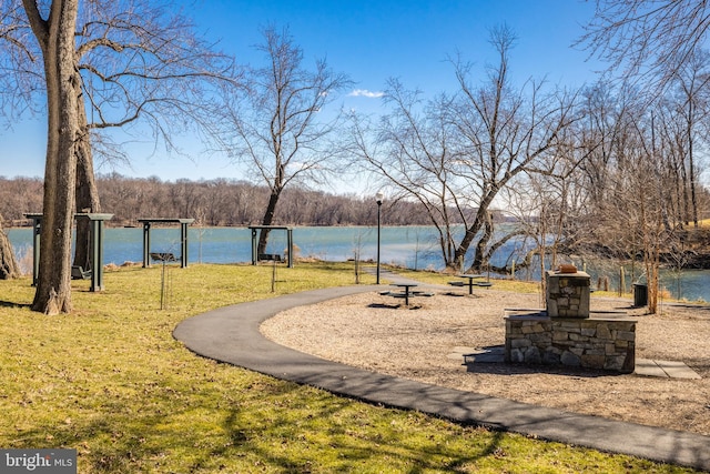 surrounding community with a water view and a lawn