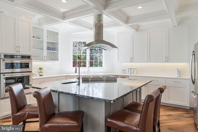 kitchen with coffered ceiling, a breakfast bar, and white cabinetry