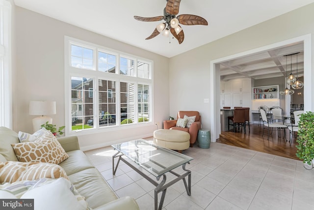 living room with coffered ceiling, light tile patterned flooring, ceiling fan, and a wealth of natural light