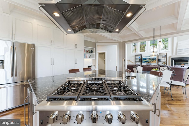kitchen featuring coffered ceiling, ventilation hood, white cabinetry, ornamental molding, and appliances with stainless steel finishes