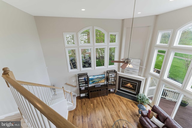 living room with a glass covered fireplace, light wood-type flooring, recessed lighting, and baseboards